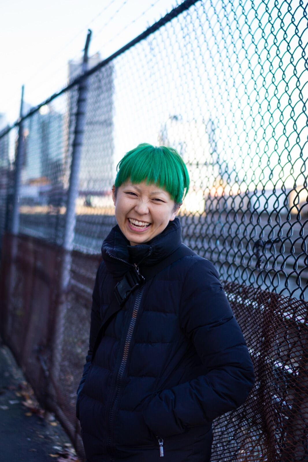 Laughing portrait by a chain-link fence