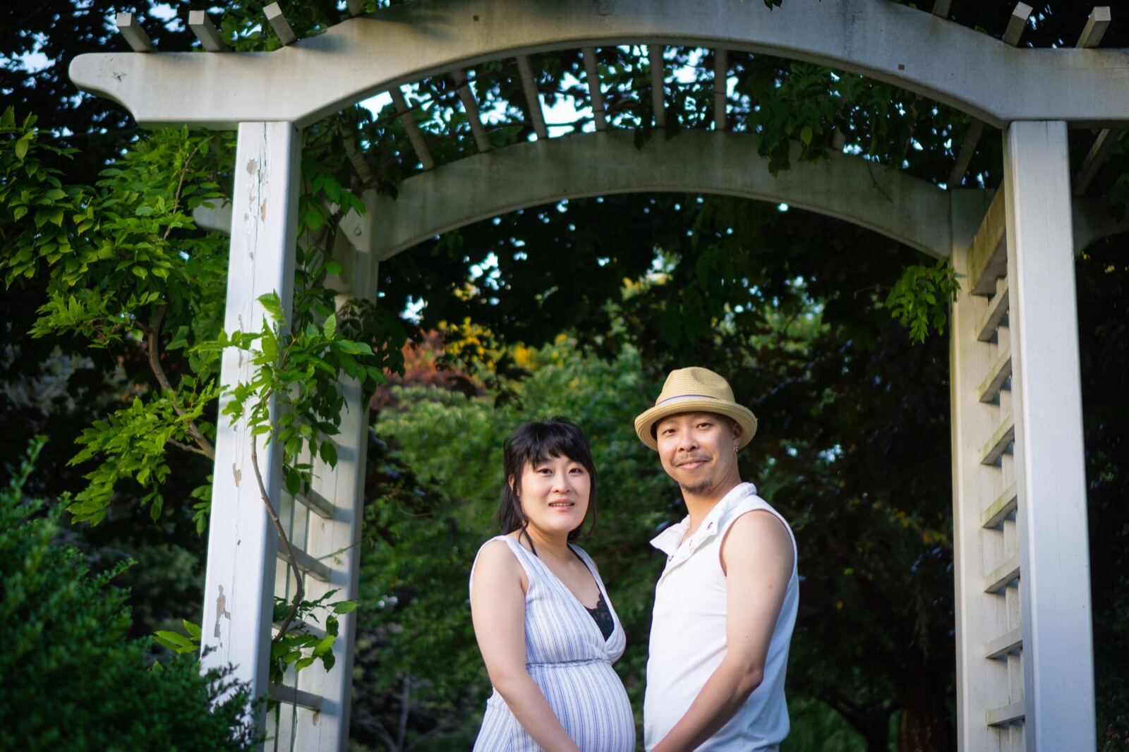 Expecting couple under a garden archway