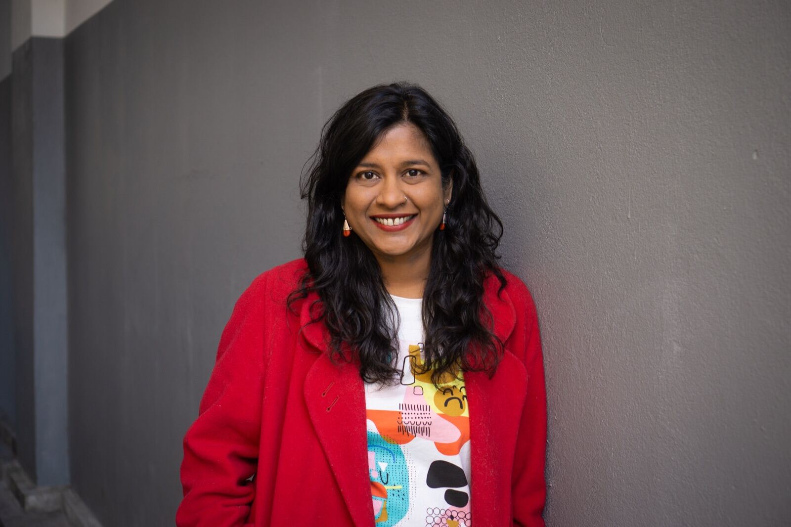Portrait in a red coat against a grey wall