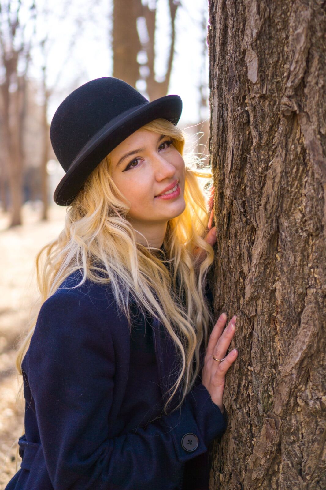 Portrait in a bowler hat leaning against a tree